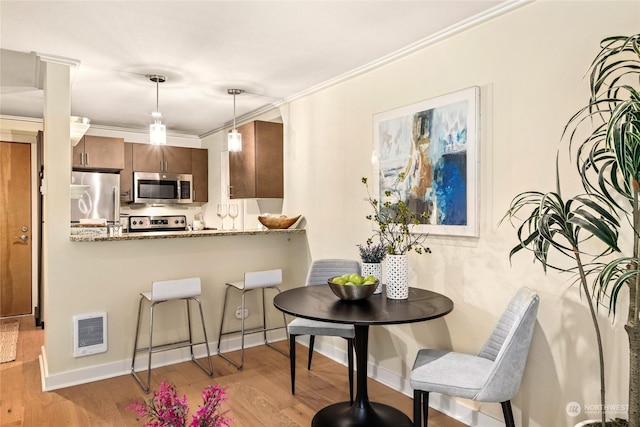 dining space featuring crown molding and light hardwood / wood-style floors