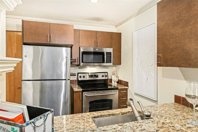 kitchen featuring stainless steel appliances, crown molding, sink, and light stone counters