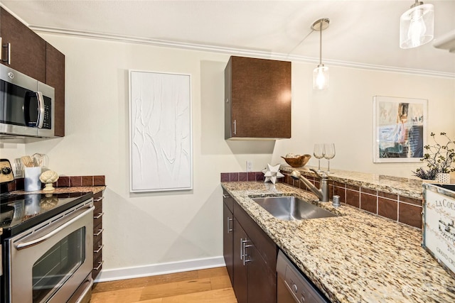 kitchen with sink, dark brown cabinets, hanging light fixtures, light wood-type flooring, and stainless steel appliances