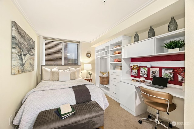 bedroom featuring crown molding, built in desk, light colored carpet, and a closet