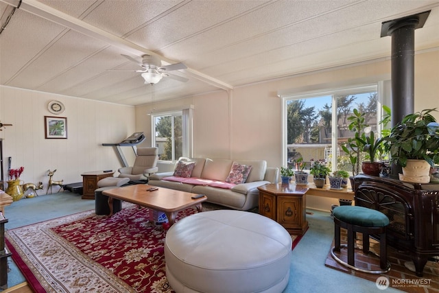 living room with ceiling fan, carpet flooring, and a wood stove