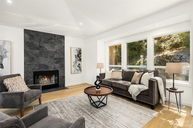 living room with a tiled fireplace and hardwood / wood-style floors