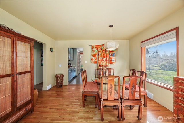 dining area with light wood-style floors, baseboards, and french doors