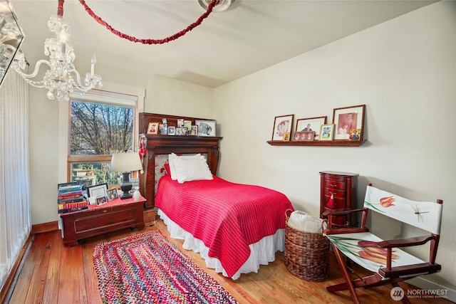 bedroom featuring baseboards, hardwood / wood-style floors, and an inviting chandelier