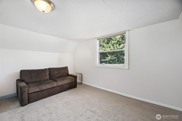 living area featuring lofted ceiling, carpet flooring, and baseboards