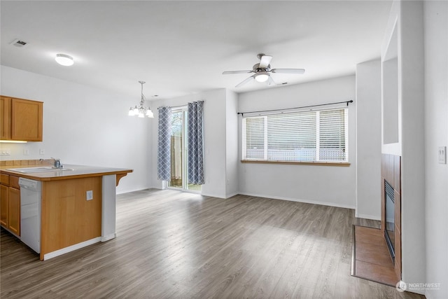 kitchen with sink, hardwood / wood-style flooring, hanging light fixtures, white dishwasher, and ceiling fan with notable chandelier