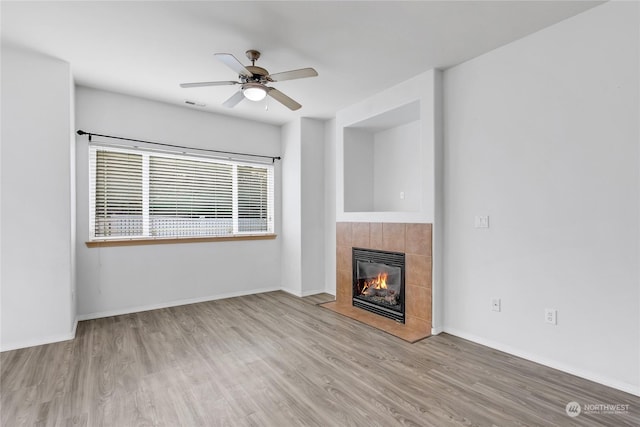 unfurnished living room featuring ceiling fan, light hardwood / wood-style floors, and a tile fireplace