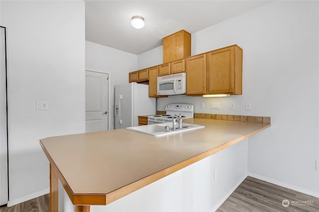 kitchen with hardwood / wood-style floors, white appliances, and kitchen peninsula