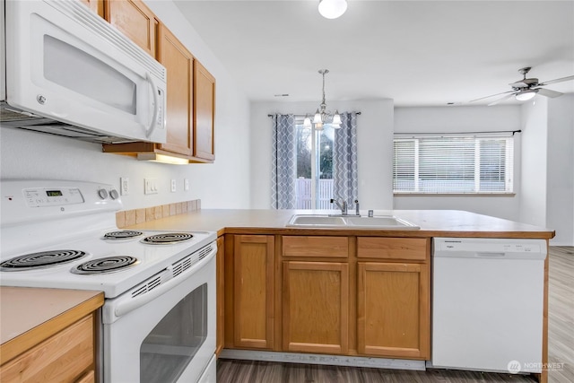 kitchen featuring sink, kitchen peninsula, pendant lighting, white appliances, and ceiling fan with notable chandelier