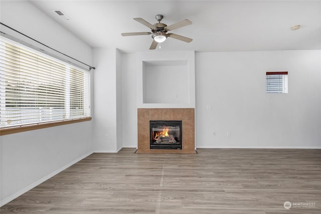 unfurnished living room featuring ceiling fan, a tile fireplace, and light hardwood / wood-style flooring