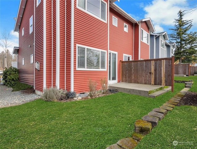 view of side of property featuring a patio and a lawn