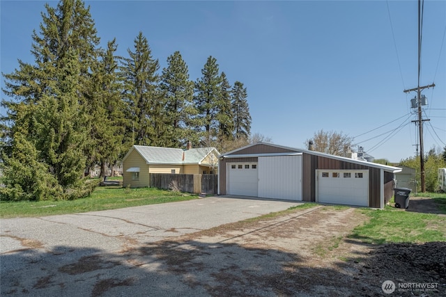 view of front of house featuring fence, driveway, an outdoor structure, and a garage