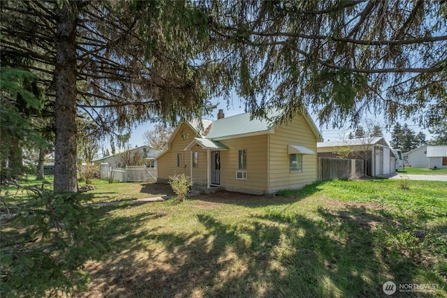 view of side of property with a yard, a chimney, and fence