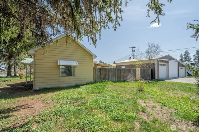 view of side of property featuring fence, an outbuilding, a yard, and a garage