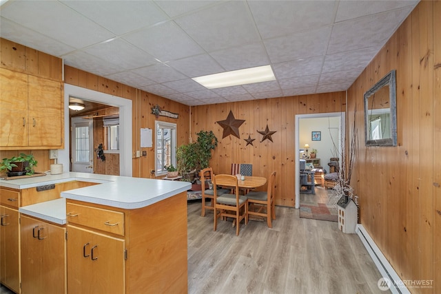kitchen with light wood-type flooring, light countertops, wood walls, and a baseboard radiator