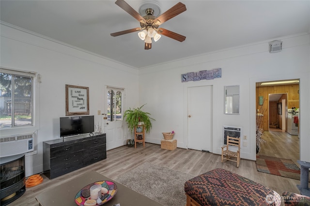 living area featuring an AC wall unit, crown molding, heating unit, wood finished floors, and ceiling fan