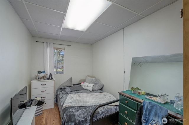 bedroom with wood finished floors and a drop ceiling