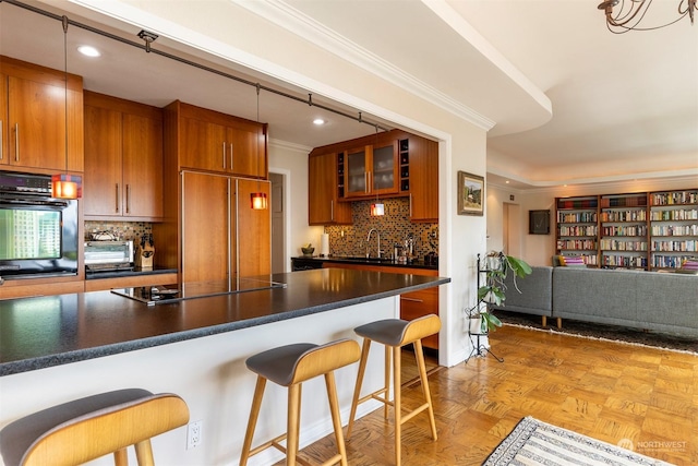 kitchen featuring a kitchen bar, hanging light fixtures, ornamental molding, light parquet flooring, and black appliances