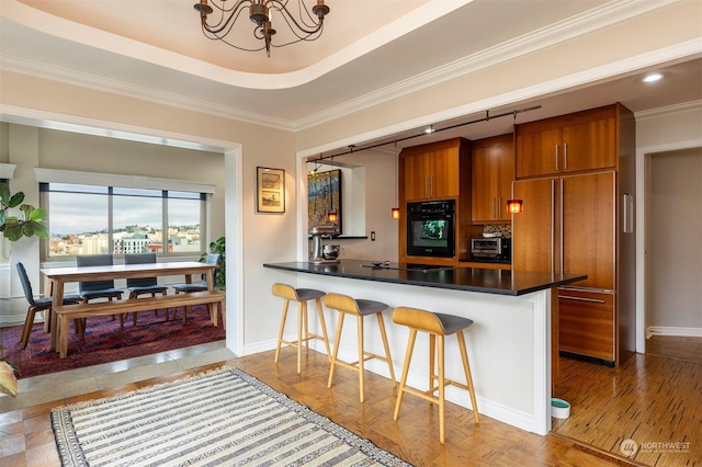 kitchen with a breakfast bar, black appliances, a chandelier, ornamental molding, and kitchen peninsula