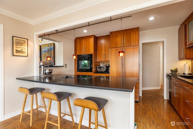 kitchen with decorative light fixtures, kitchen peninsula, a breakfast bar area, and black appliances