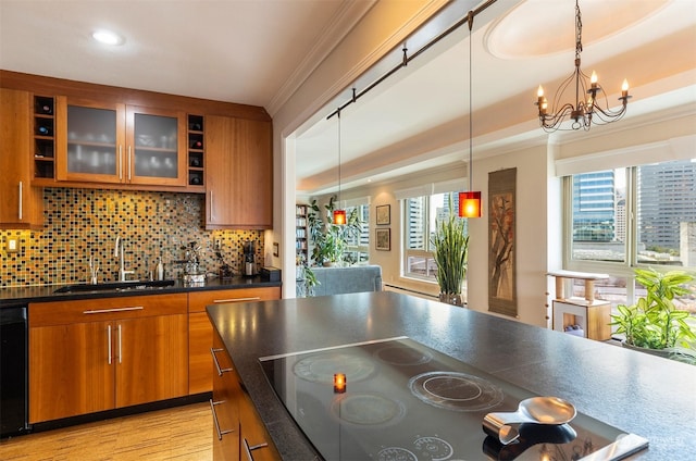 kitchen with pendant lighting, sink, crown molding, tasteful backsplash, and black appliances