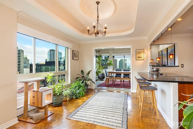 interior space with light parquet floors, plenty of natural light, an inviting chandelier, and a tray ceiling