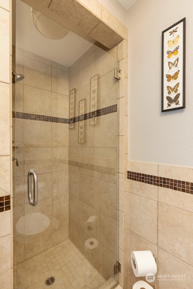 bathroom with an enclosed shower and tile walls