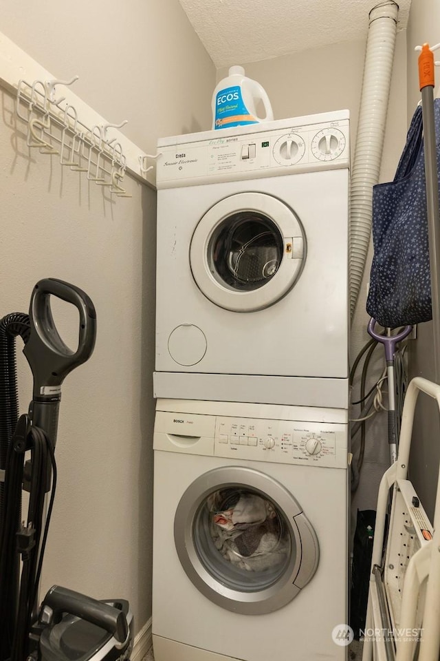 laundry room featuring stacked washer and dryer and a textured ceiling