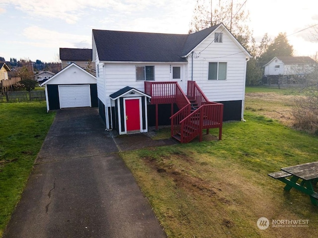 view of front of house with a garage, an outbuilding, and a front lawn