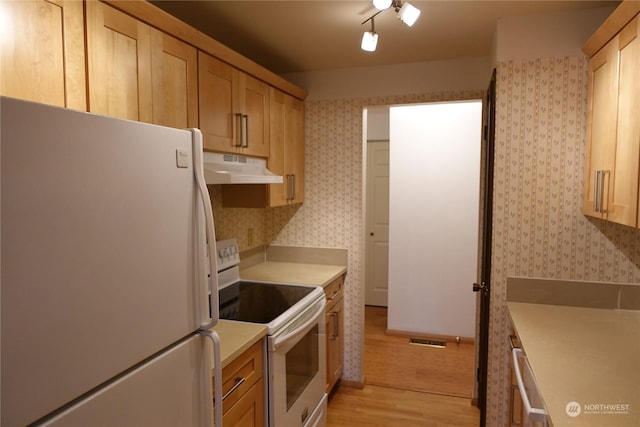 kitchen with white appliances, light brown cabinetry, and light hardwood / wood-style floors