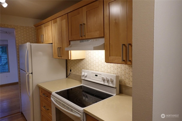 kitchen with hardwood / wood-style flooring, white appliances, and tasteful backsplash