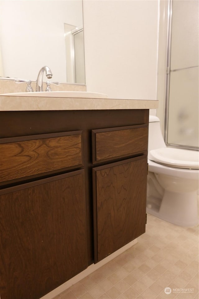 bathroom featuring vanity, toilet, and a shower with shower door