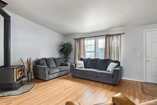 living room with hardwood / wood-style flooring, a wood stove, and a textured ceiling