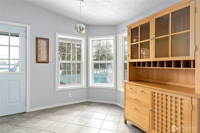 unfurnished dining area featuring a wealth of natural light, a textured ceiling, and light tile patterned floors