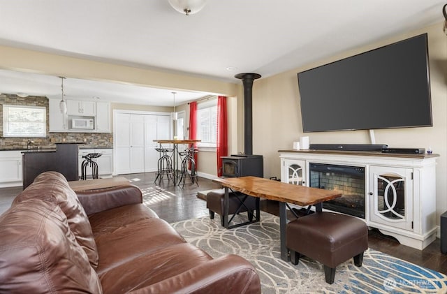 living room with dark hardwood / wood-style floors, a wood stove, and a fireplace