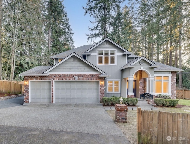 craftsman-style house with an attached garage, driveway, fence, and brick siding