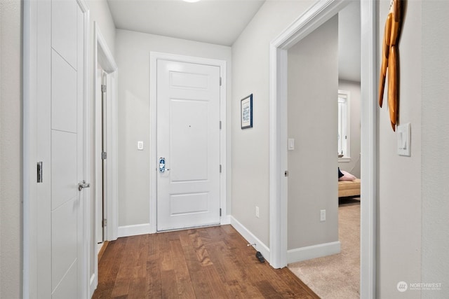 corridor with baseboards and wood finished floors