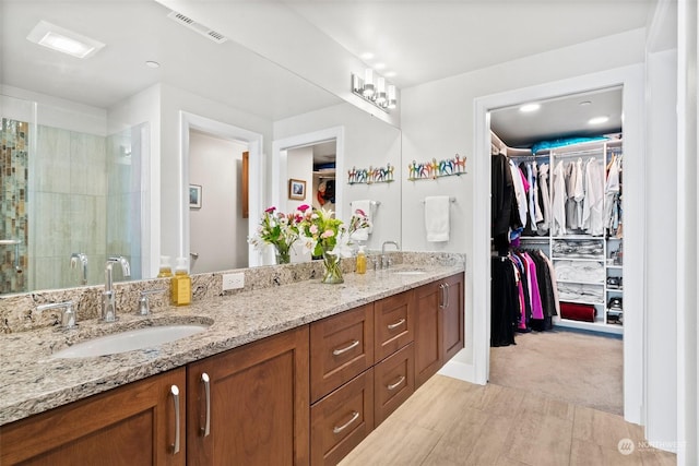 full bathroom with visible vents, double vanity, a sink, and a walk in closet