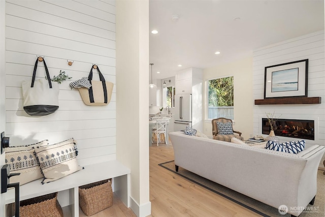 interior space with a sink, recessed lighting, a glass covered fireplace, and light wood-style floors