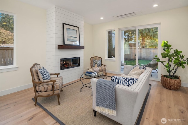 interior space with light wood-type flooring, a large fireplace, visible vents, and recessed lighting