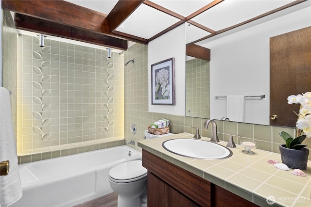 full bathroom featuring tile walls, vanity, tiled shower / bath combo, toilet, and tasteful backsplash