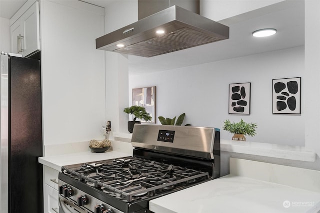 kitchen with light stone counters, extractor fan, white cabinets, and appliances with stainless steel finishes