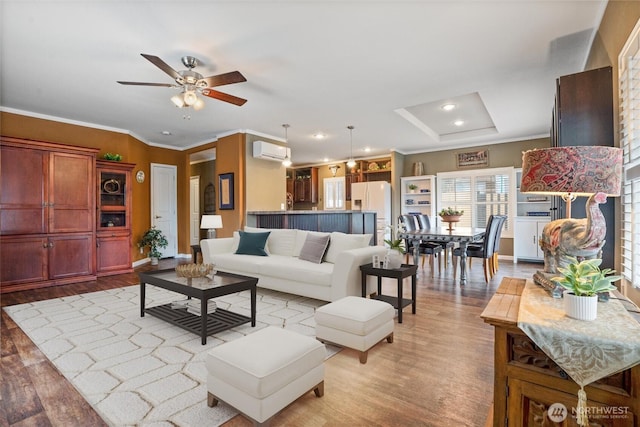 living room with ceiling fan, ornamental molding, a wall unit AC, and light hardwood / wood-style flooring