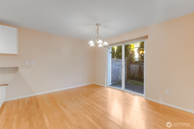 unfurnished dining area featuring an inviting chandelier and light hardwood / wood-style floors