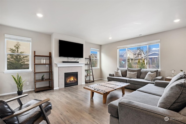 living room featuring a tiled fireplace and light wood-type flooring