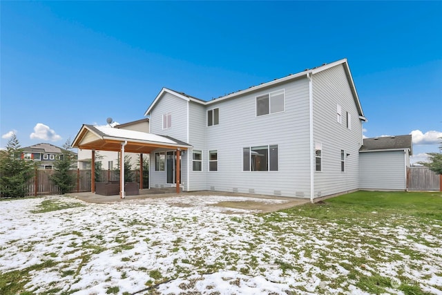 snow covered house with a patio and a lawn