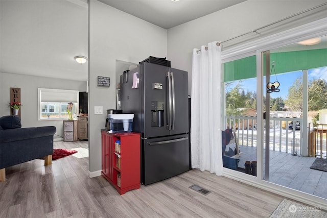 kitchen with stainless steel refrigerator with ice dispenser, plenty of natural light, and light wood-type flooring