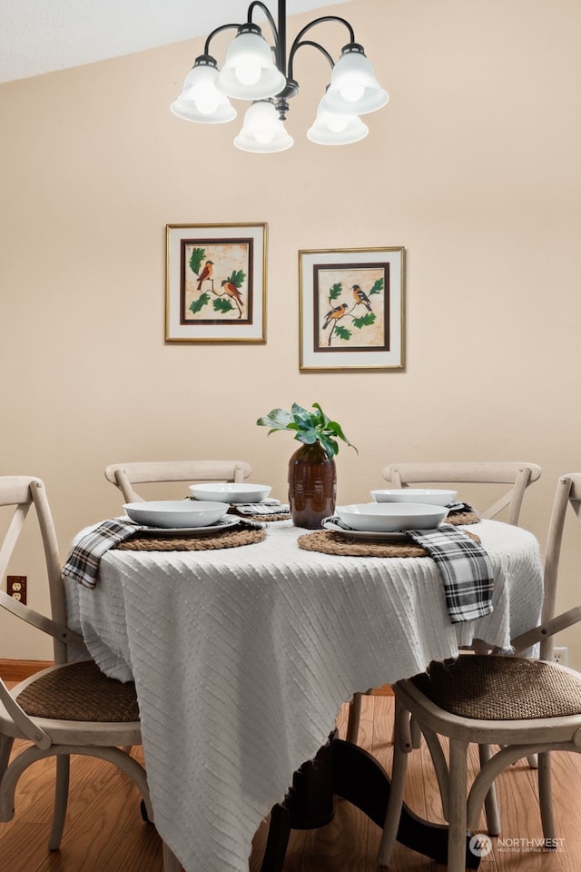 dining space with hardwood / wood-style flooring and an inviting chandelier