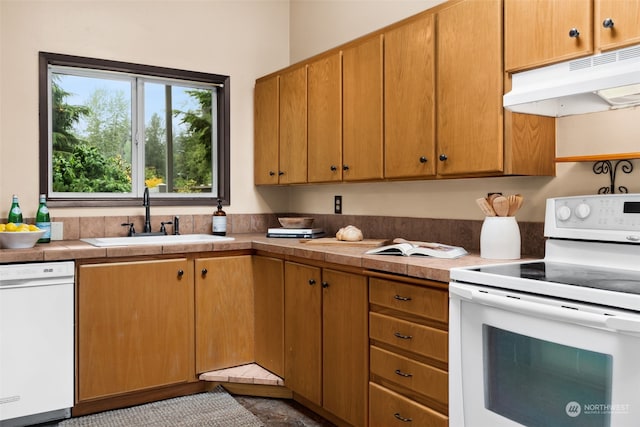 kitchen featuring white appliances, tile counters, and sink