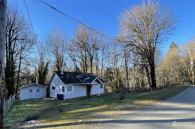 view of home's exterior featuring central air condition unit, a yard, fence, and an outdoor structure